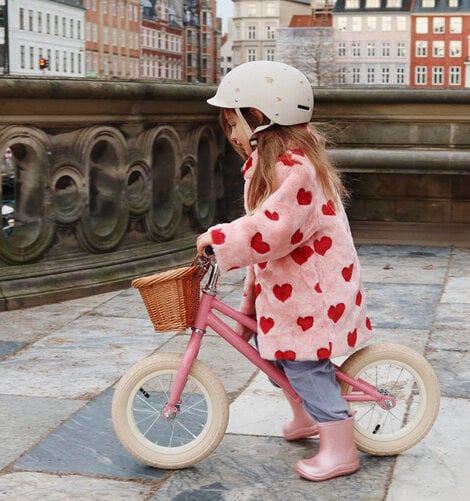 Lille pige der køre på en glimtende lyserød balancecykel