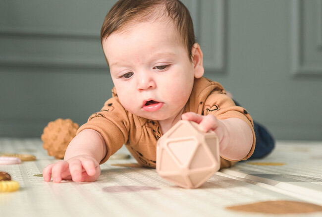 Baby der ligger og kigger på sansebold fra Edushape