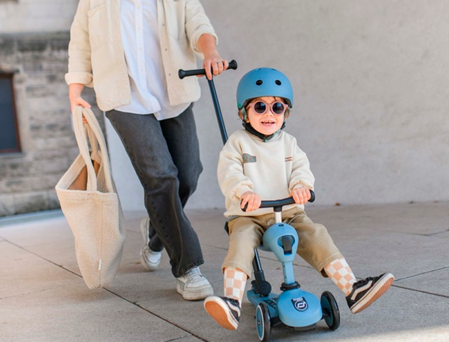 Et glad barn der sidder på en Scoot and Ride push and go