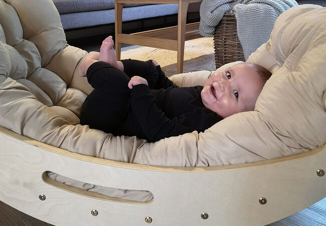 Smilende baby der ligger i en hemmingsen klatrebue